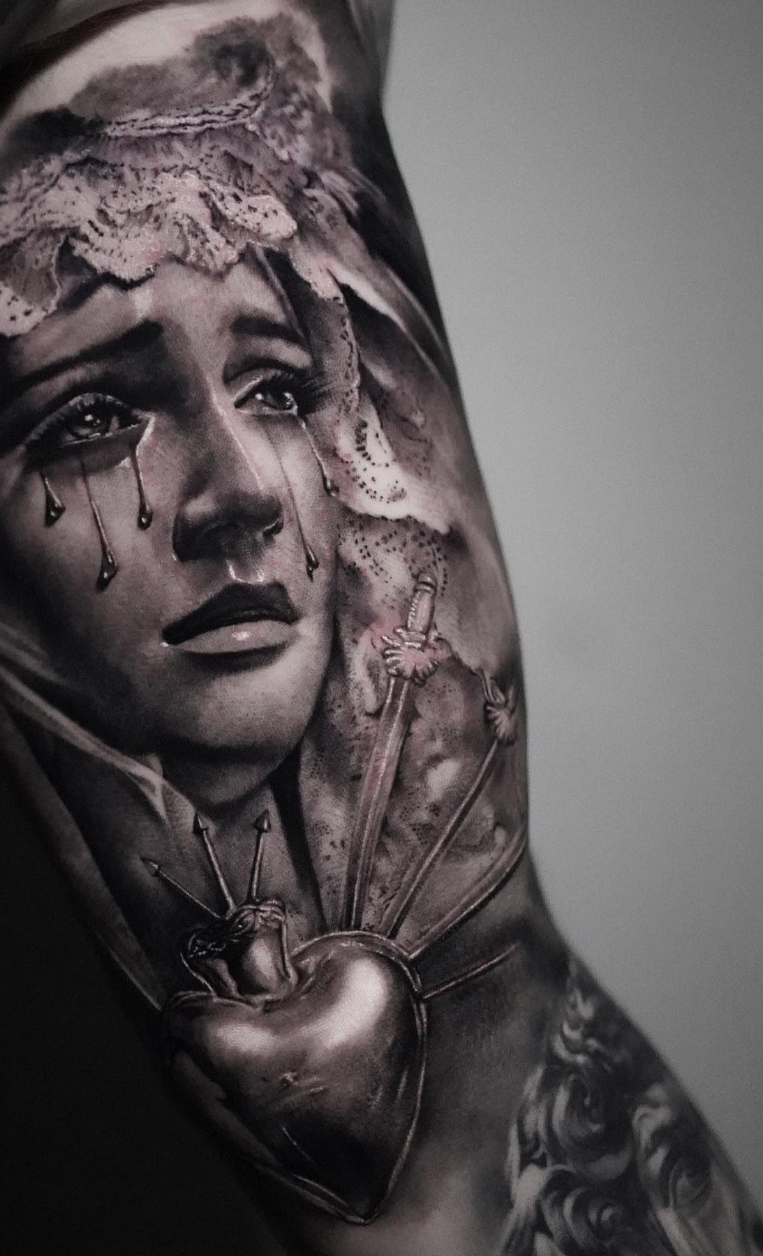 Sacred heart tattoo with a weeping woman wearing a lace veil in realism style.