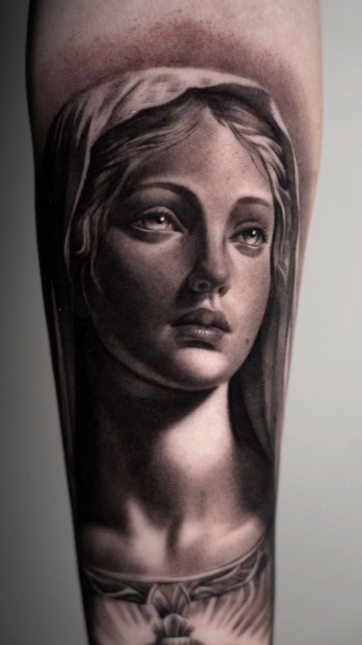 Realistic black and grey tattoo of a veiled woman looking upward on an arm.