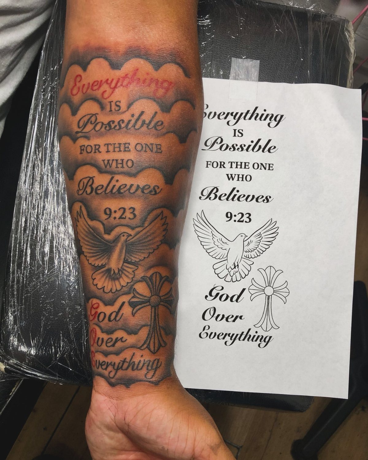 Forearm tattoo with Bible verse 9:23, a dove, and a religious cross design.